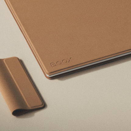 Corner of a tan Onyx Boox smart cover with the BOOX logo and a rolled stylus loop beside it