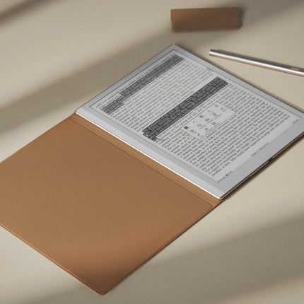 Onyx Boox Go 10.3 e-reader with the tan smart cover folded back, resting on a desk beside a stylus