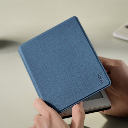 Hands holding an Onyx Boox Go 6 in a navy smart cover above a desk with a stylus