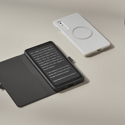 Onyx Boox Palma 2 in a dark flip cover on a beige surface beside a white back cover and a glass