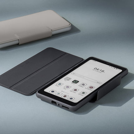 Onyx Boox Palma 2 Pro with its dark flip cover folded back, beside a white accessory and a cup