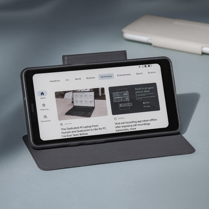 Onyx Boox Palma 2 Pro in a dark flip cover propped up like a stand on a grey surface
